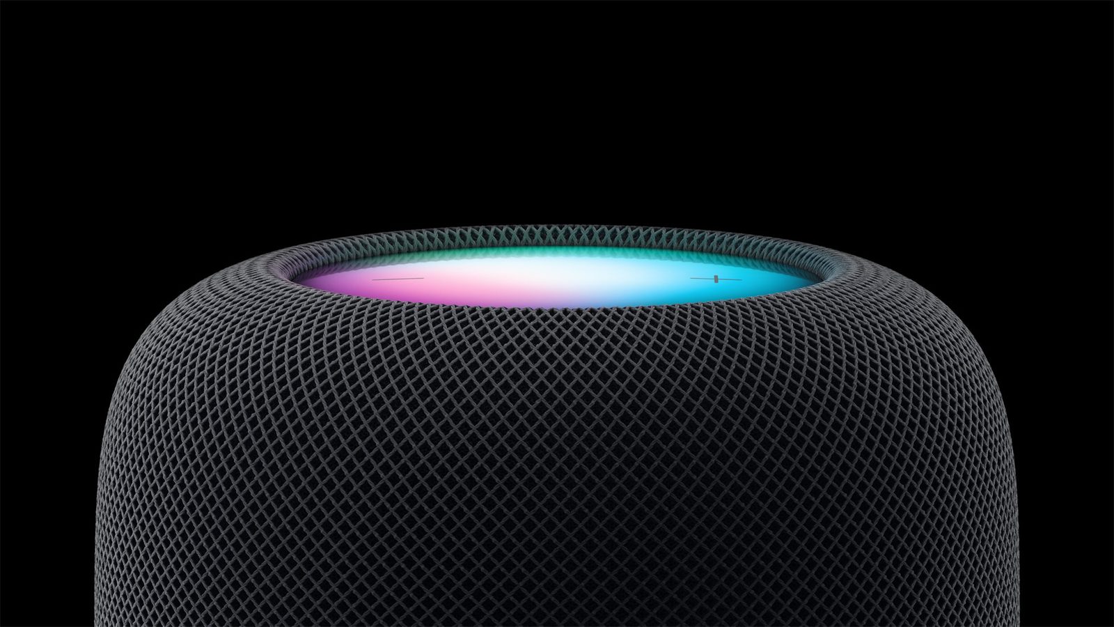 Närbild på en HomePod i midnatt med Siris färgade ljus på ovansidan mot svart bakgrund.