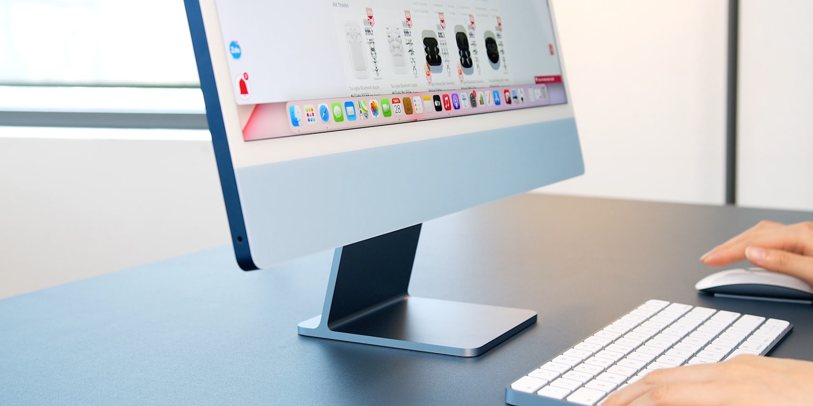 En blå iMac på ett skrivbord med Magic Keyboard och Magic Mouse