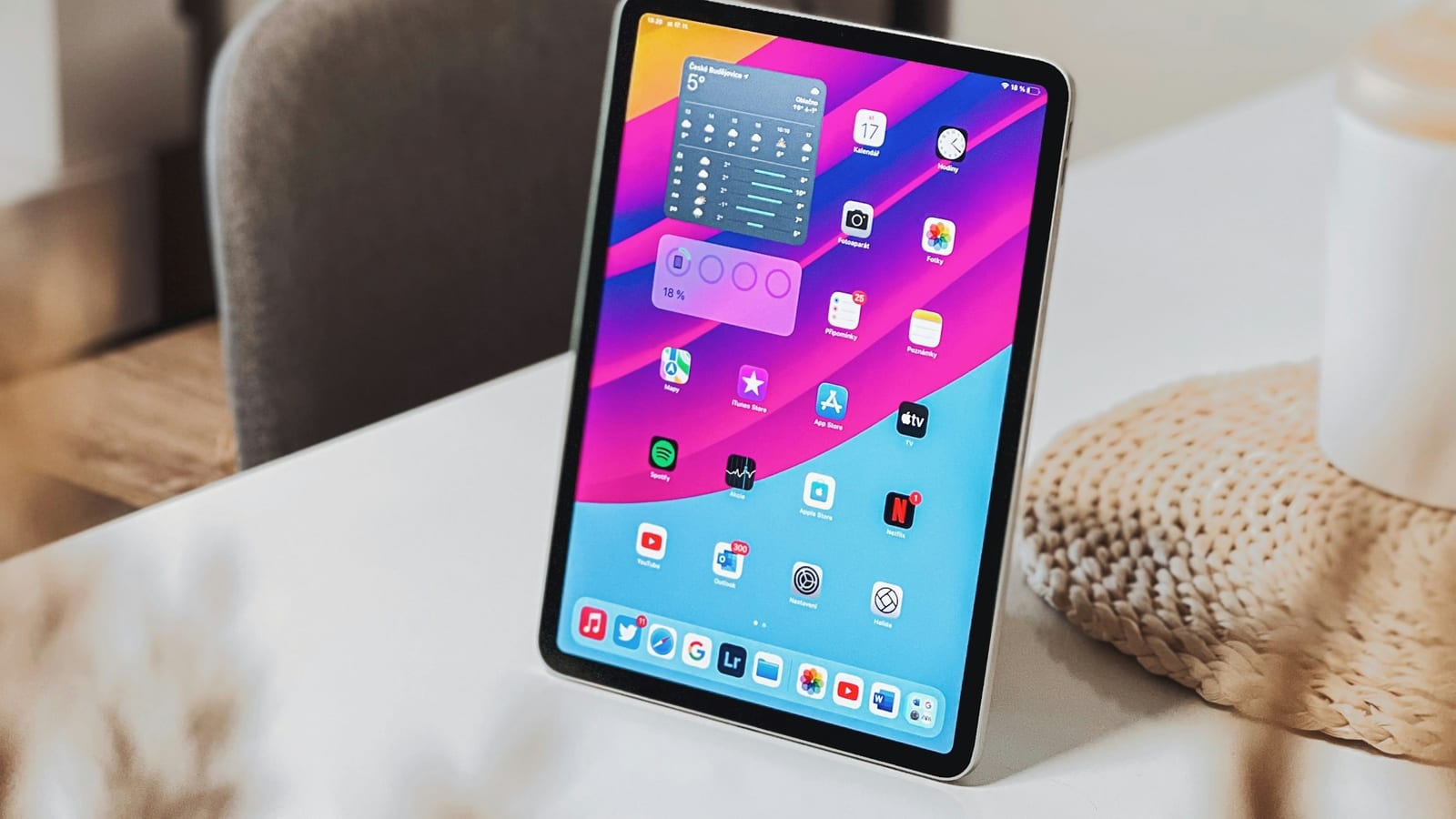 iPad Air uppställd på ett vitt bord med hemskärmen och appar synliga.