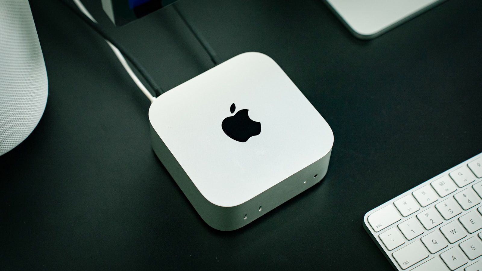 Mac mini med M4 på ett mörkt skrivbord bredvid ett Magic Keyboard